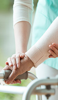 Health care worker helping patient use a walker.