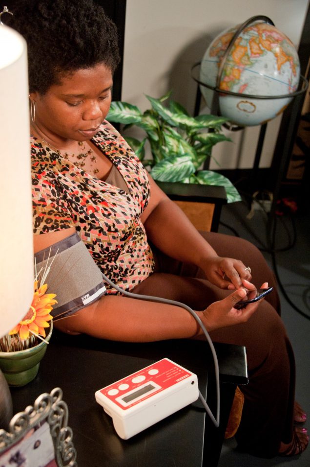Woman using a home blood pressure monitor.