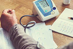 A man taking his own blood pressure with an at home monitor.